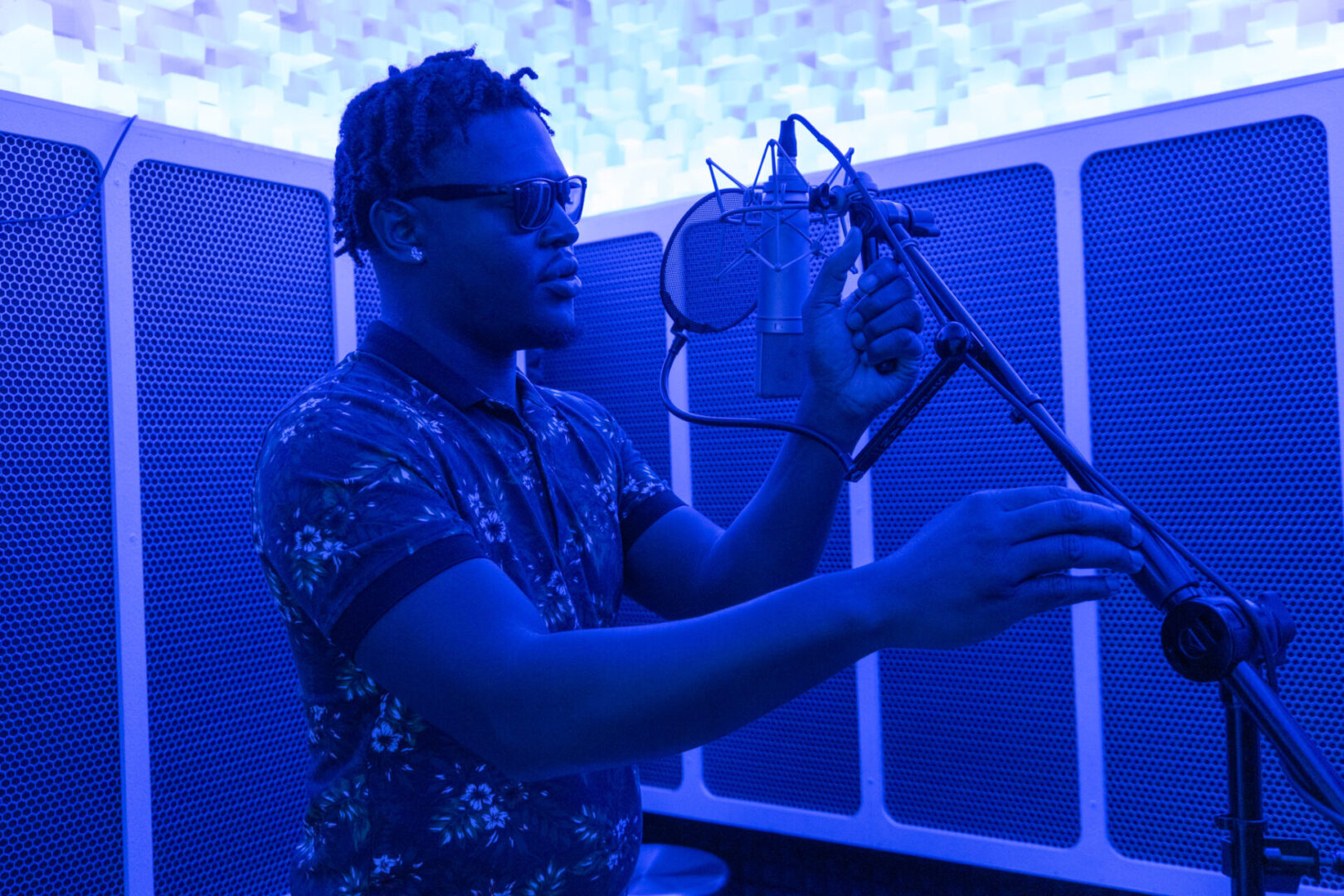 A man holding up a microphone in front of a blue wall.