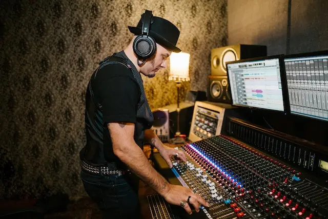 A man in black shirt and headphones near a mixing board.