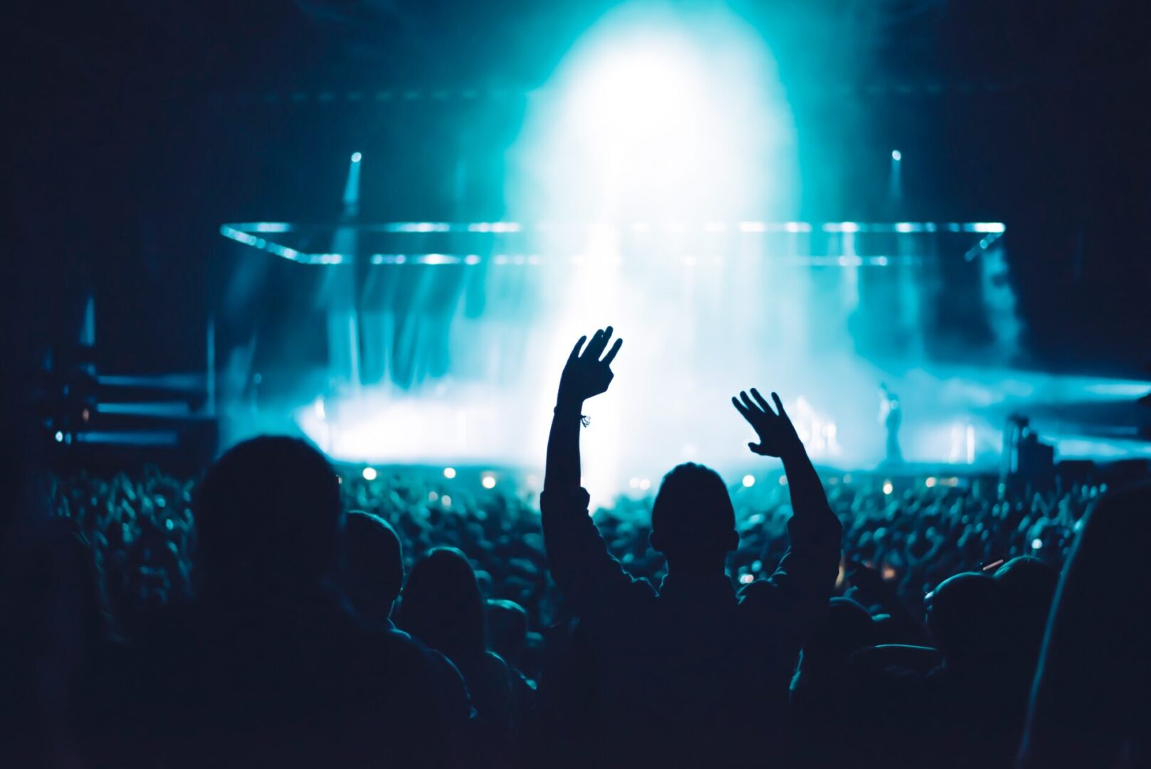 A crowd of people at an event with their hands up.