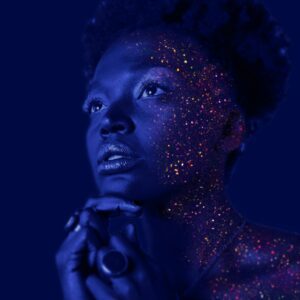 A person with blue light on their face and hands in prayer.