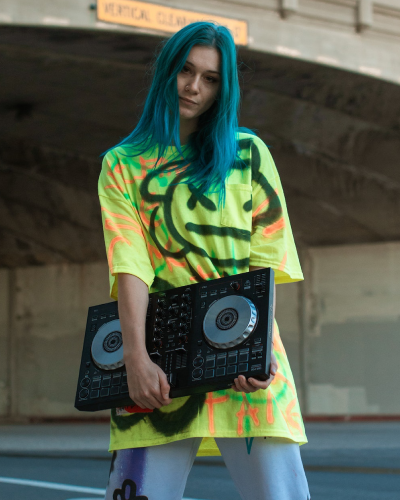 A woman with blue hair holding two dj turntables.